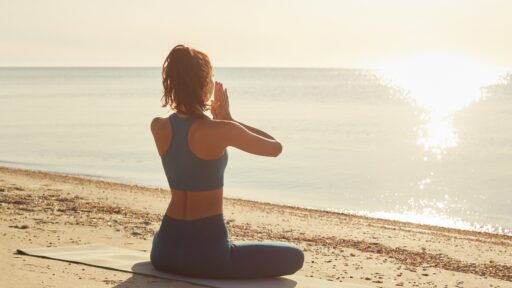Wellnessurlaub - Frau meditiert am Strand