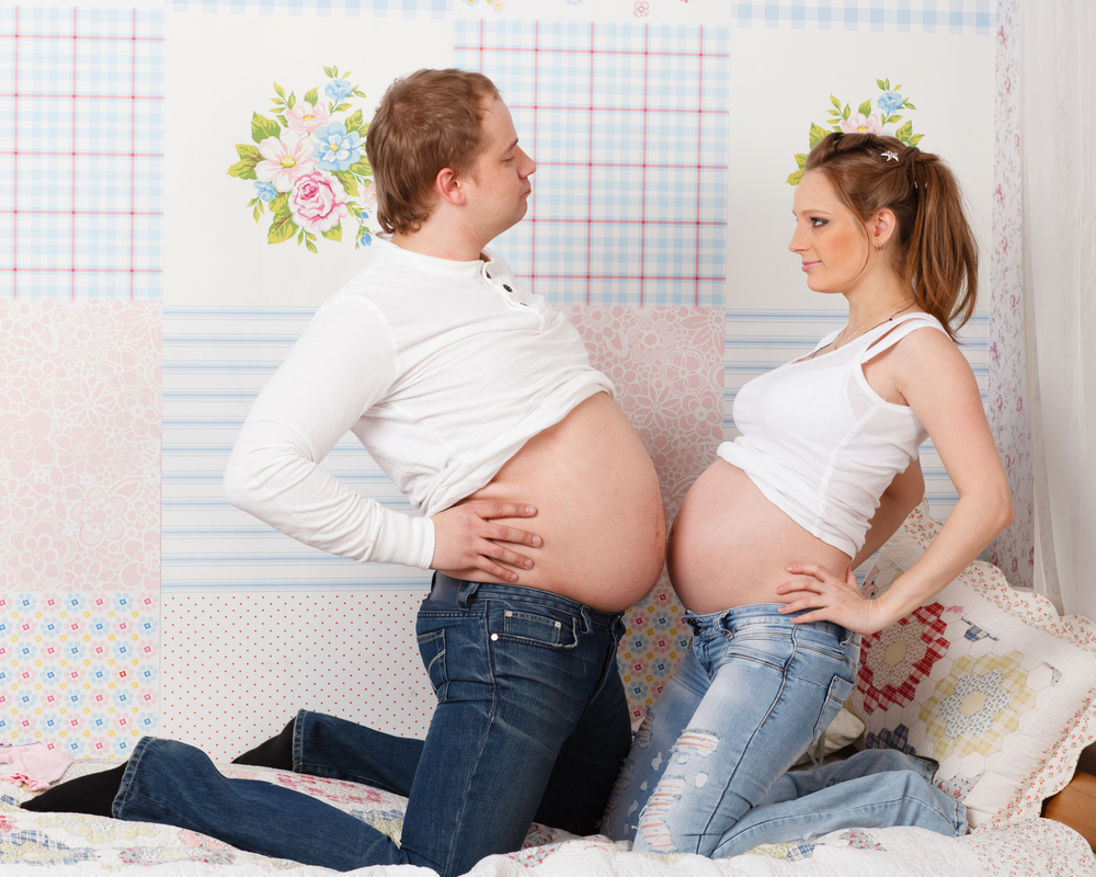 Gleicher Humor verbindet - Schwangere Frau und Mann mit rundem Bauch machen Spaß