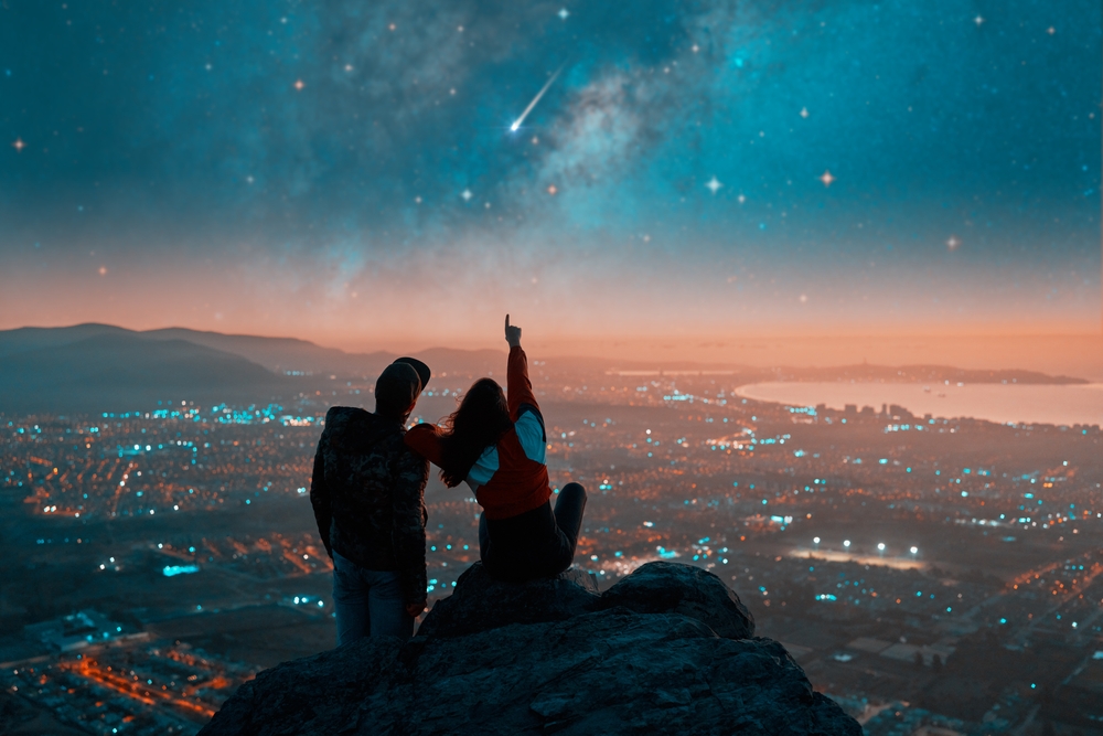 Paar schaut sich über der Stadt den Sternenhimmel an